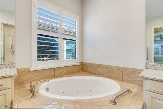 bathroom with a wealth of natural light, vanity, and a whirlpool tub