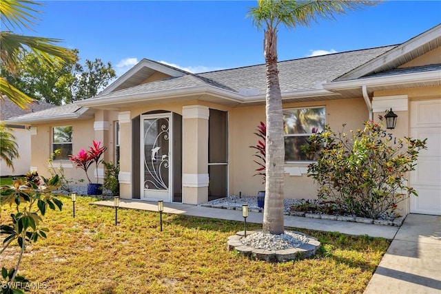 entrance to property with a shingled roof, stucco siding, and an attached garage