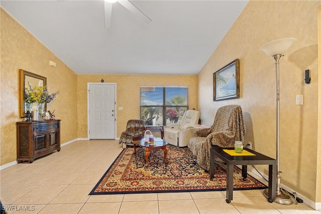 living area with light tile patterned floors, ceiling fan, vaulted ceiling, and baseboards