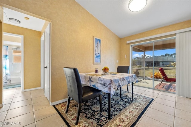 dining room featuring light tile patterned floors, a healthy amount of sunlight, and vaulted ceiling