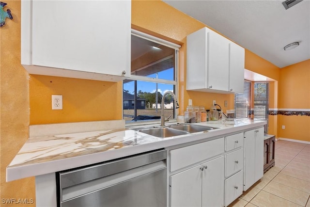 kitchen featuring white cabinetry, stainless steel dishwasher, a sink, light countertops, and light tile patterned flooring