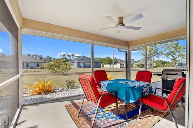 sunroom featuring a ceiling fan and a residential view