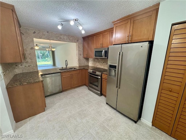 kitchen featuring dark stone countertops, a sink, brown cabinets, and stainless steel appliances