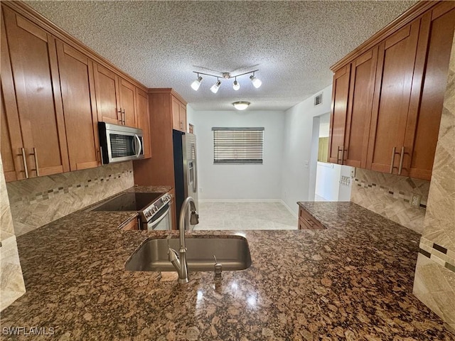 kitchen featuring brown cabinets, appliances with stainless steel finishes, decorative backsplash, and a sink