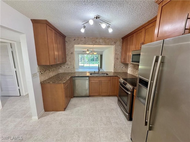 kitchen featuring track lighting, brown cabinetry, stainless steel appliances, and light tile patterned flooring