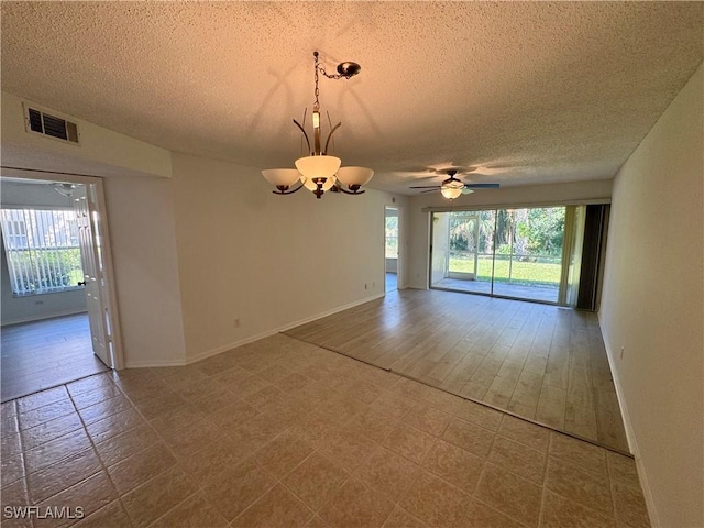 empty room featuring a textured ceiling, visible vents, a wealth of natural light, and baseboards