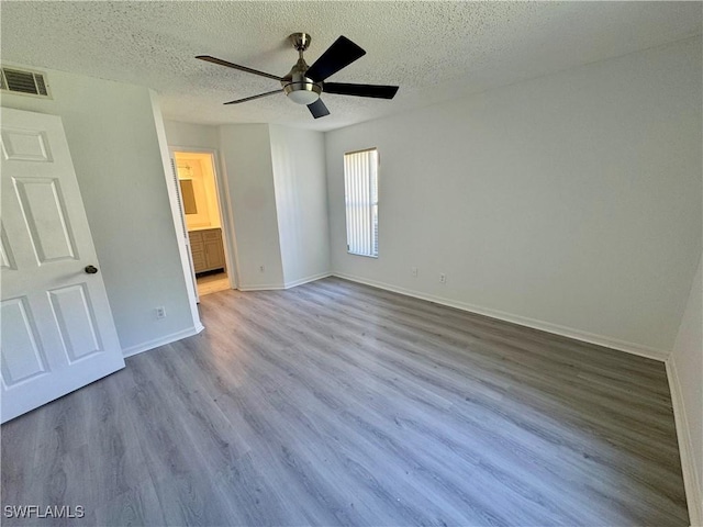 unfurnished bedroom featuring a textured ceiling, visible vents, ceiling fan, baseboards, and wood finished floors