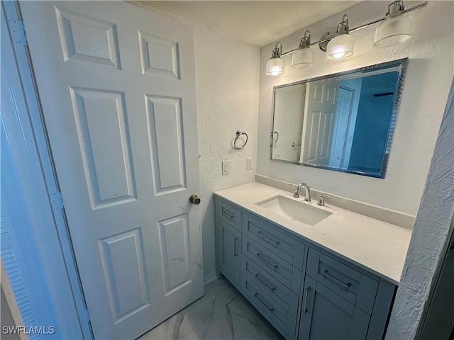 bathroom with a textured wall, vanity, and marble finish floor