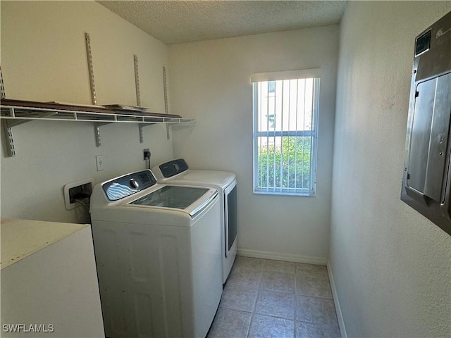 laundry area featuring a textured ceiling, washing machine and clothes dryer, laundry area, and baseboards