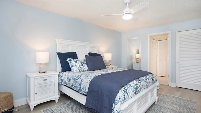 bedroom with ceiling fan, baseboards, and light wood-type flooring