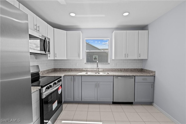kitchen with tasteful backsplash, stainless steel appliances, gray cabinetry, and a sink