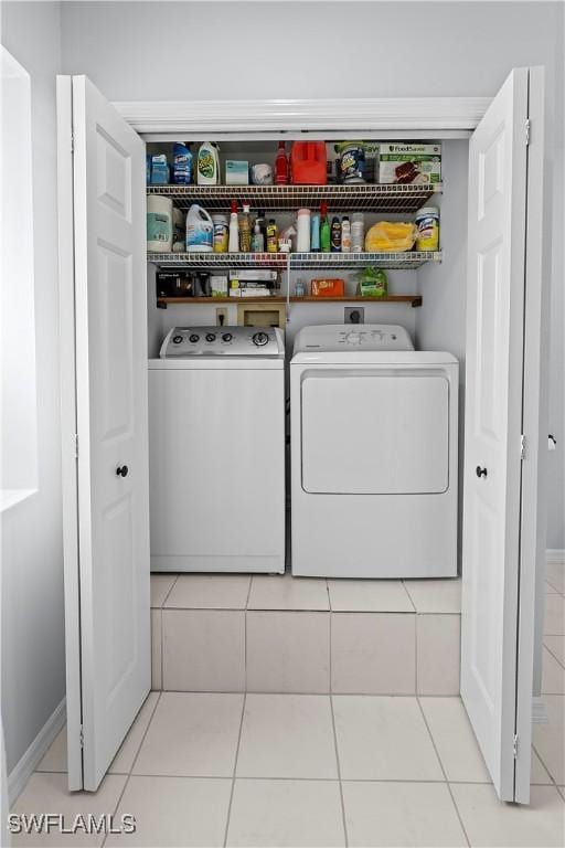 laundry area with tile patterned floors, baseboards, washer and dryer, and laundry area