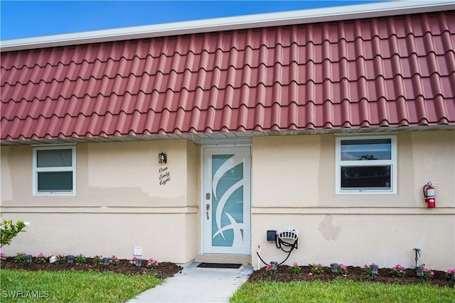 property entrance with a tiled roof and stucco siding