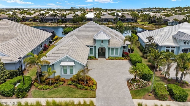 view of front of home featuring a residential view, driveway, a water view, and stucco siding