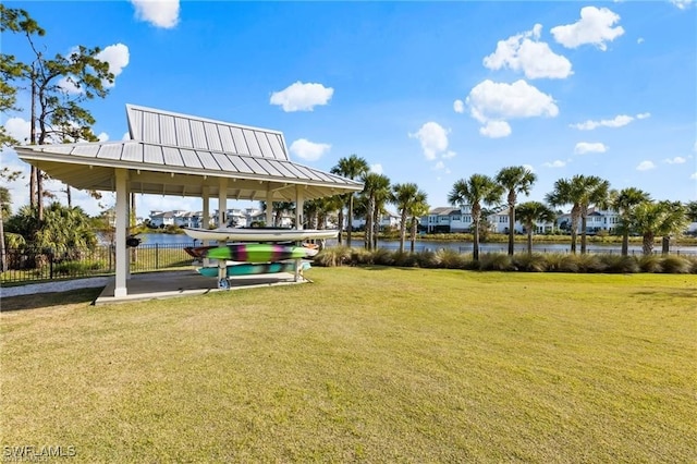 view of home's community with a gazebo, a yard, a water view, and fence