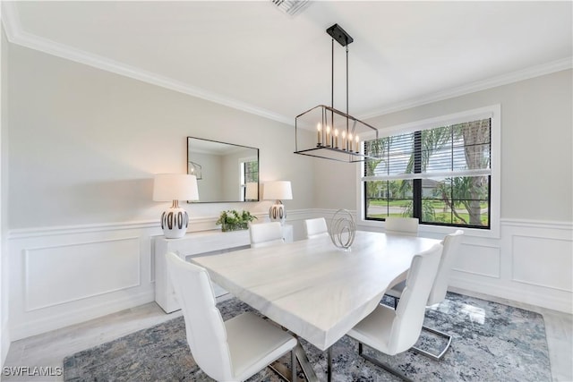 19128 Elston Way, Estero, FL 33928 - dining space with crown molding, a wainscoted wall, a decorative wall, a chandelier, and light wood-style floors