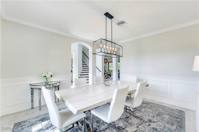 19128 Elston Way, Estero, FL 33928 - dining area with arched walkways, crown molding, a wainscoted wall, a decorative wall, and stairs