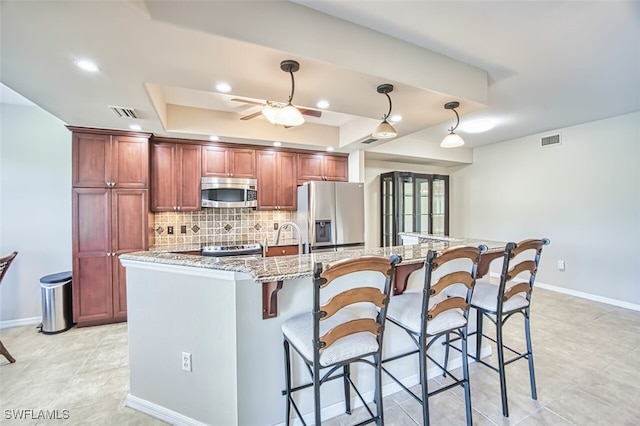 11029 Mill Creek Way Unit 406, Fort Myers, FL 33913 - kitchen featuring appliances with stainless steel finishes, decorative backsplash, ceiling fan, a breakfast bar area, and light stone counters