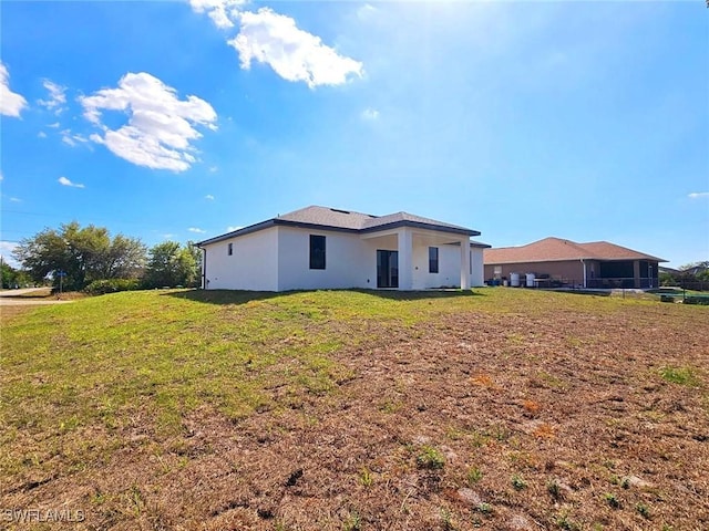 3400 23rd St W, Lehigh Acres, FL 33971 - rear view of property with a lawn and stucco siding