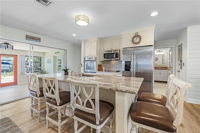 3797 Emerald Ave, Saint James City, FL 33956 - kitchen with a kitchen bar, light stone countertops, visible vents, and appliances with stainless steel finishes