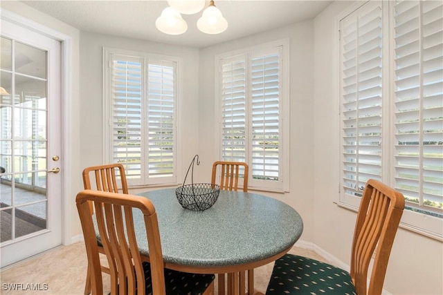 dining area with a wealth of natural light, baseboards, and an inviting chandelier