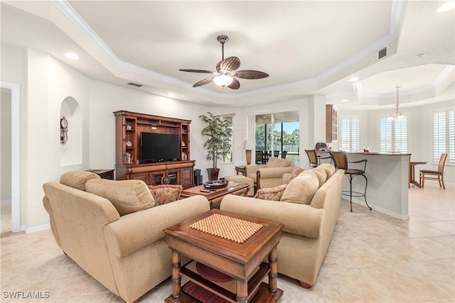 living room with visible vents, a healthy amount of sunlight, crown molding, and a tray ceiling