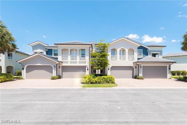view of front of home featuring a balcony, driveway, an attached garage, and stucco siding