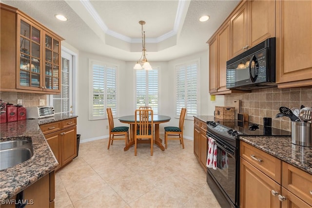 kitchen featuring decorative backsplash, a tray ceiling, crown molding, black appliances, and baseboards