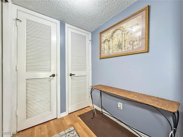 1632 Spoonbill Ln Unit B, Naples, FL 34105 - doorway with a textured ceiling, light wood-style flooring, and baseboards
