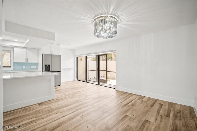 517 Lake Louise Cir Unit 101, Naples, FL 34110 - unfurnished living room featuring a chandelier, light wood-style flooring, baseboards, and recessed lighting