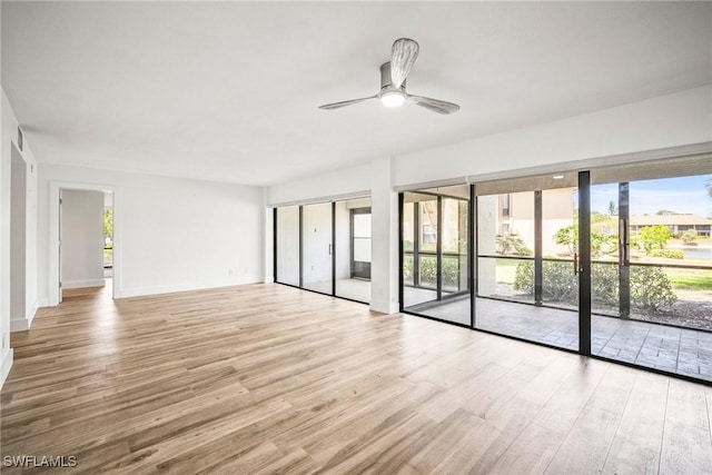 517 Lake Louise Cir Unit 101, Naples, FL 34110 - empty room with wood finished floors, a ceiling fan, and baseboards