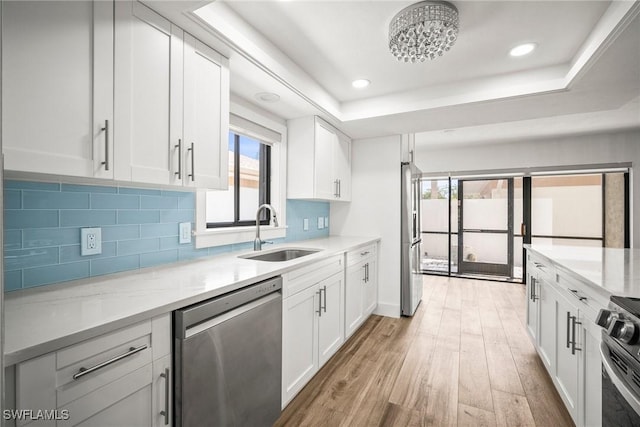 517 Lake Louise Cir Unit 101, Naples, FL 34110 - kitchen featuring stainless steel appliances, a sink, light wood finished floors, decorative backsplash, and white cabinetry