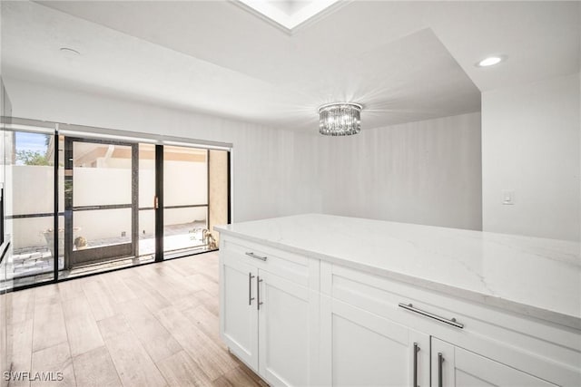 517 Lake Louise Cir Unit 101, Naples, FL 34110 - kitchen with light wood-style flooring, white cabinets, light stone countertops, a chandelier, and recessed lighting
