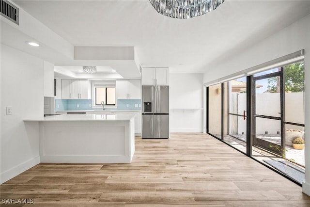 517 Lake Louise Cir Unit 101, Naples, FL 34110 - kitchen with stainless steel fridge, a sink, light countertops, white cabinets, and baseboards