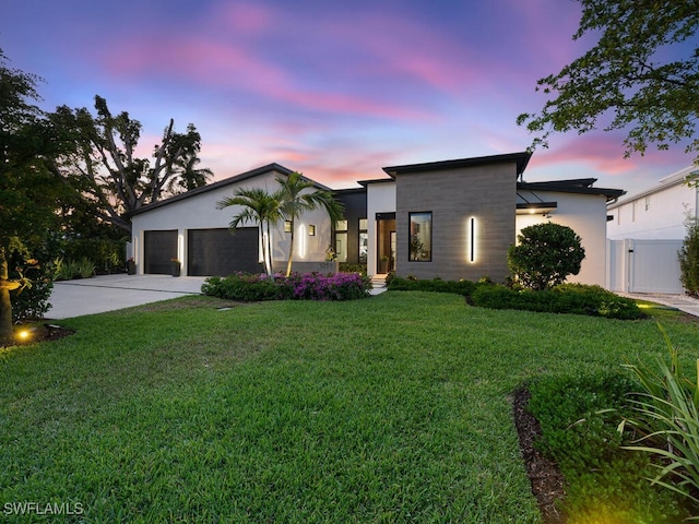 contemporary house with a gate, fence, driveway, a lawn, and a garage