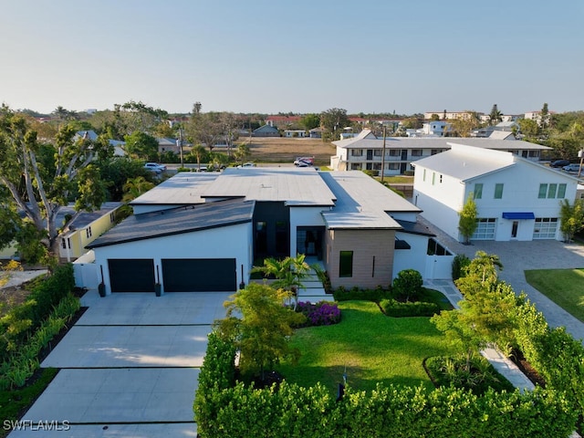 view of front facade featuring a residential view, an attached garage, a front yard, and concrete driveway