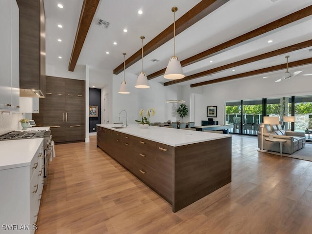 kitchen with beam ceiling, a sink, visible vents, dark brown cabinetry, and modern cabinets