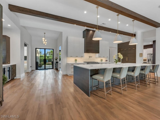 kitchen with wall chimney exhaust hood, modern cabinets, stainless steel fridge, and beamed ceiling