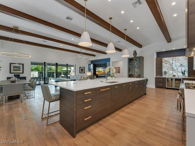 kitchen with a sink, dark brown cabinets, open floor plan, visible vents, and light countertops