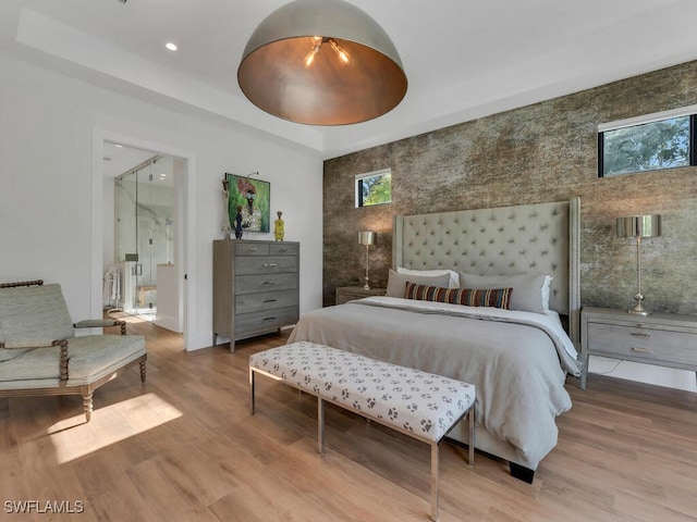 bedroom with baseboards, recessed lighting, wood finished floors, connected bathroom, and a raised ceiling
