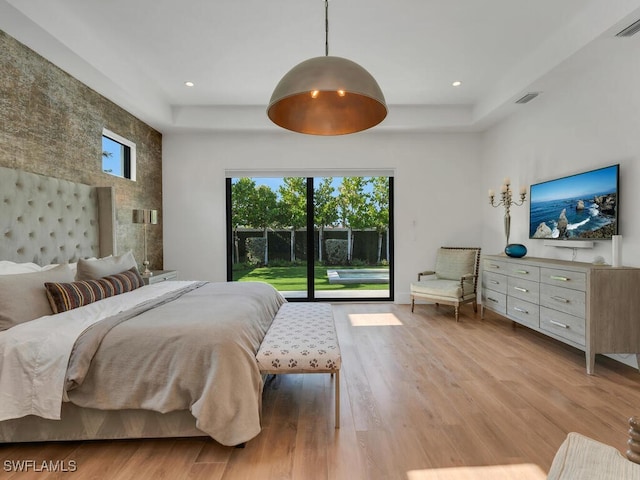 bedroom featuring access to outside, multiple windows, and a raised ceiling