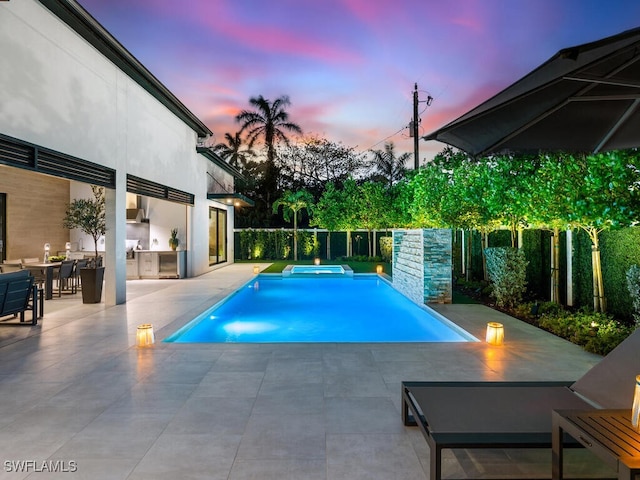 view of swimming pool featuring a pool with connected hot tub, area for grilling, and a patio