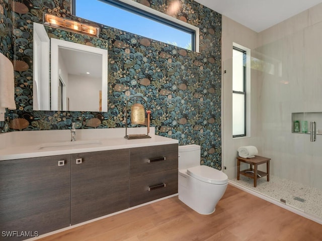 bathroom with wallpapered walls, wood finished floors, vanity, and toilet