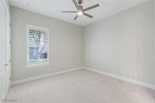 empty room featuring baseboards, ceiling fan, and light colored carpet