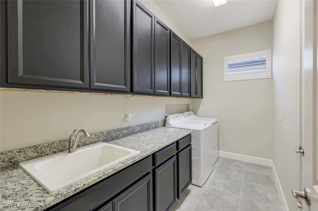 clothes washing area with cabinet space, light tile patterned flooring, a sink, separate washer and dryer, and baseboards