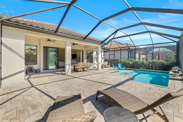 outdoor pool with a lanai, a ceiling fan, and a patio area