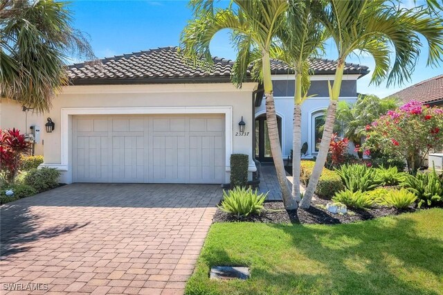 view of front of house with a garage, a front yard, decorative driveway, stucco siding, and a tiled roof