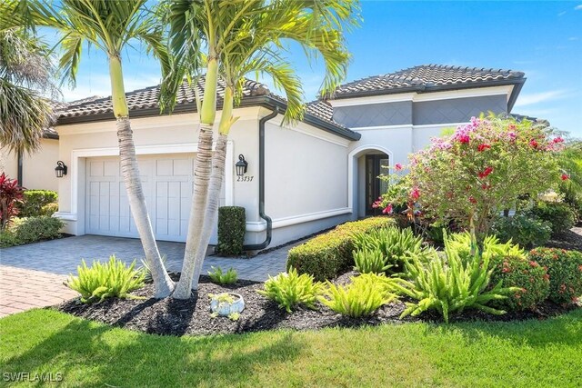 mediterranean / spanish house featuring an attached garage, driveway, and a tile roof