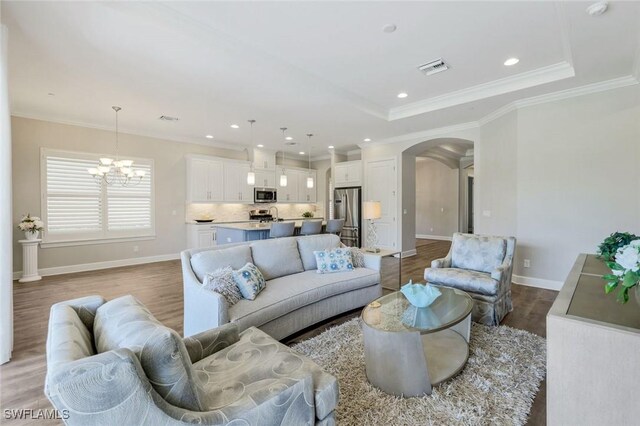 living room featuring visible vents, arched walkways, wood finished floors, baseboards, and a chandelier