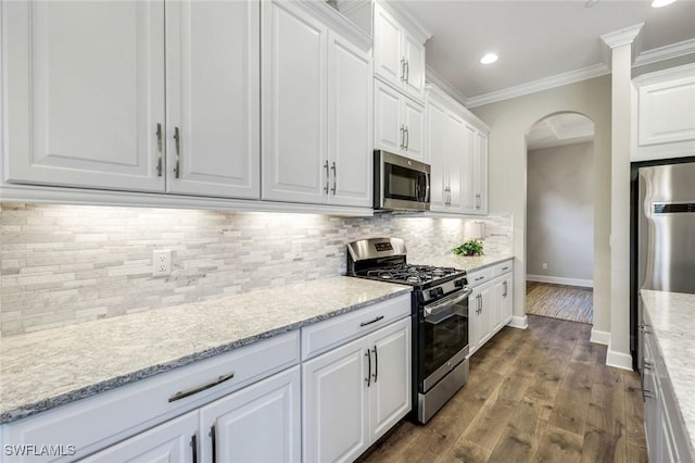 23737 Pebble Pointe Ln, Estero, FL 34135 - kitchen with appliances with stainless steel finishes, arched walkways, crown molding, white cabinetry, and baseboards